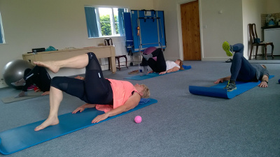 A small Pilates class working through shoulder bridges on mats